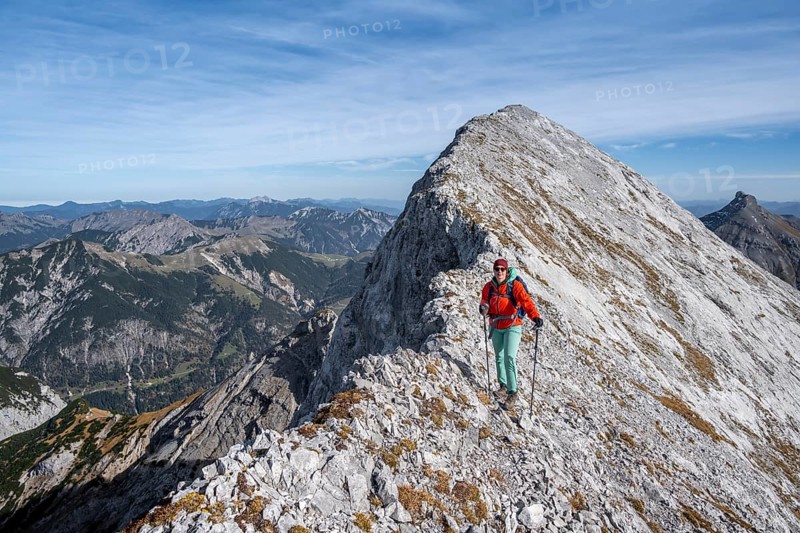 Female hiker on the summit ridge of the Gamsjoch, behind rock faces of the Laliderer Spitze, eastern Karwendel, Tyrol, Austria