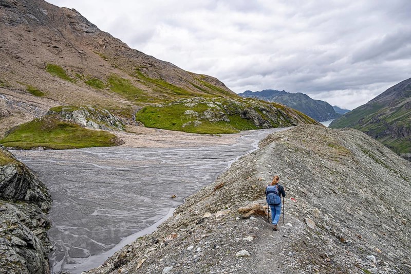 Hiker on scree trail in rocky mountain landscape under cloudy sky, Valais Alps, Valais, Switzerland