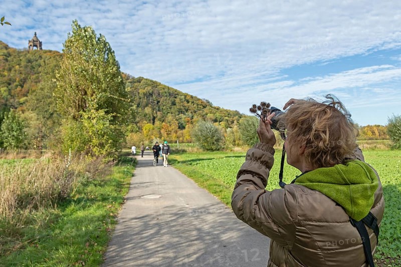Woman photographing Kaiser Wilhelm monument, mountain, forest, path, Porta Westfalica, North Rhine-Westphalia, Germany