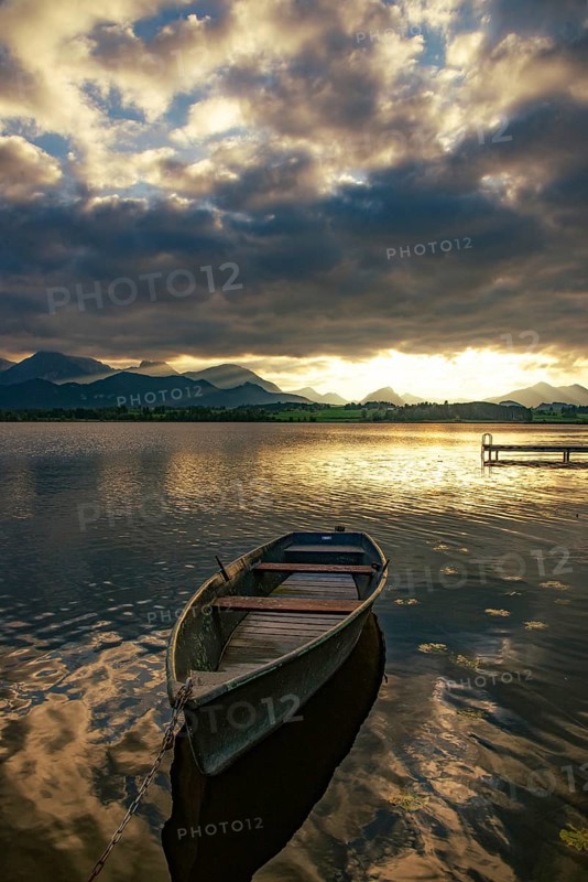 Rowing boat on Hopfensee in Allgäu at sunset in Hopfen am See, Bavaria, Germany