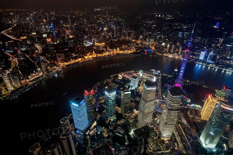 Aerial view over The Bund, Huangpu River and Lujiazui financial district with illuminated skyscrapers, in Pudong at the city Shanghai at night, China