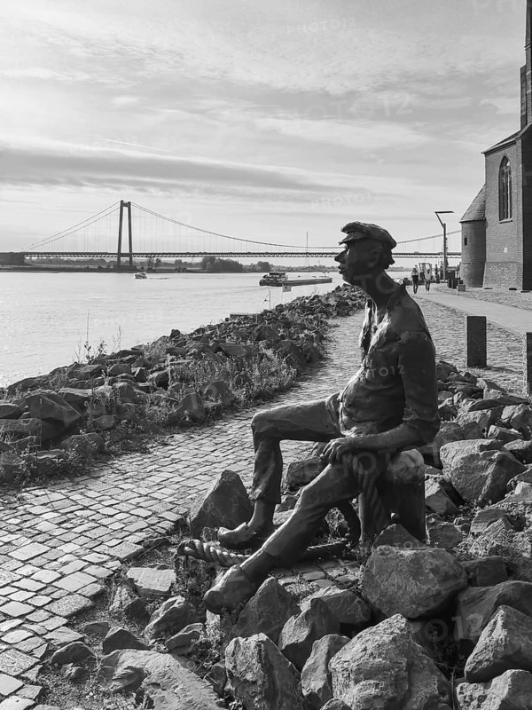 Black and white photo bronze sculpture Poortekerl looking at ships on Rhine Rhine Rhine river shipping, bronze statue by artist Heide Friede-Kinalzik, Emmerich, Lower Rhine, North Rhine-Westphalia, Germany