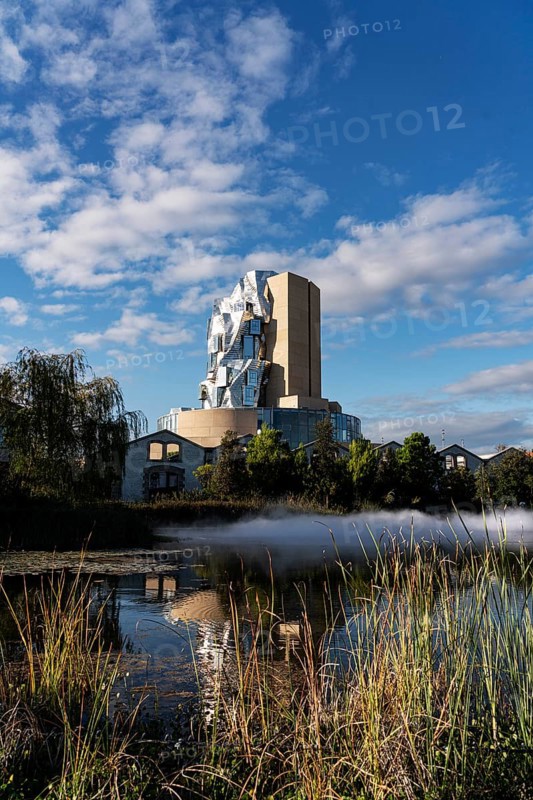 Front lake with artificial fog, Luma, 56 m high irregular tower designed by Frank Gehry, tower in the style of deconstructivism, Arles, France