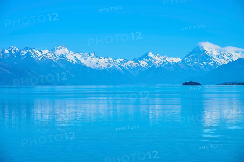 Calm lake with snow-capped mountains Mount Cook and a small island in the background, Lake Pukaki Viewpoint, Pukaki, Canterbury, South Island, New Zealand