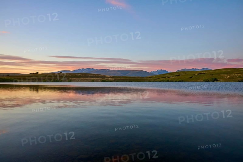 Lake with calm water and mountains in the background with a pink-blue sky, Lake McGregor, Tekapo, Canterbury, South Island, New Zealand