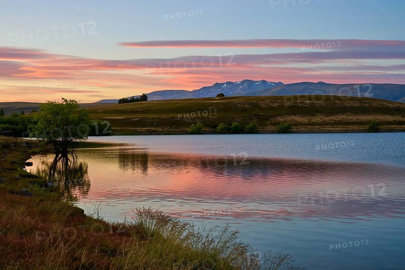 Reflecting lake with mountains in the background at sunrise with pink sky, Lake McGregor, Tekapo, Canterbury, South Island, New Zealand