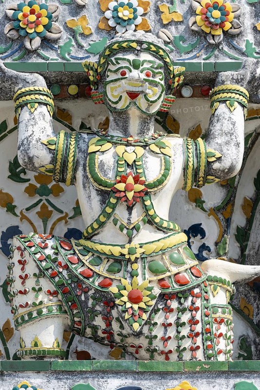 Demon figures (yaksha) supporting the central prang of Wat Arun decorated with colorful ceramic and porcelain ornaments, Thonburi, Bangkok, Thailand