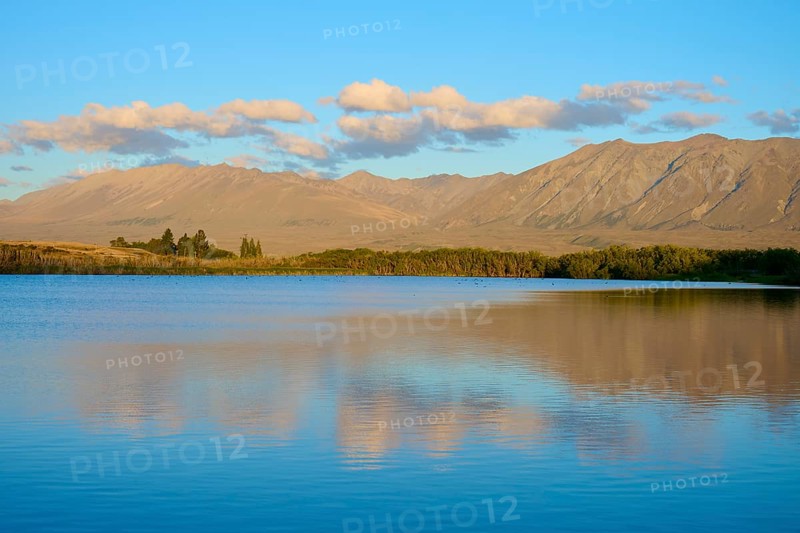 Evening over a calm lake with mountain range and beautiful cloud formation, Lake McGregor, Tekapo, Canterbury, South Island, New Zealand
