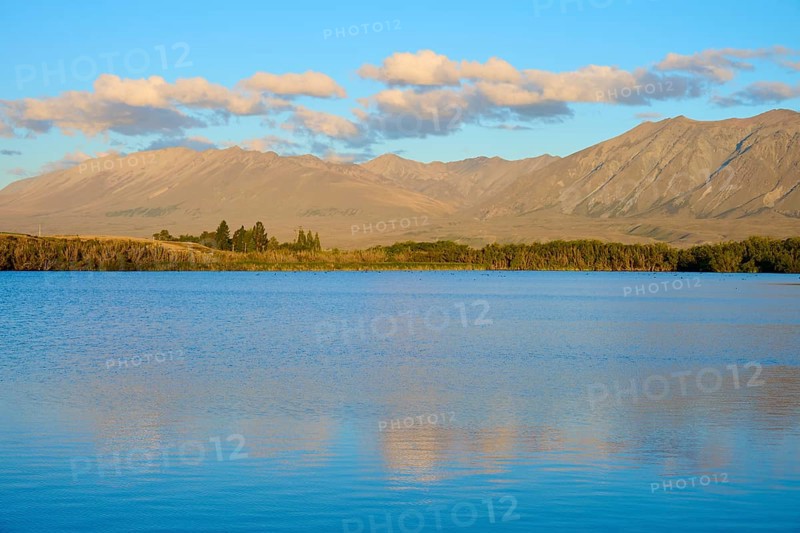 Extensive seascape in evening light with rolling mountains and cloudy skies, Lake McGregor, Tekapo, Canterbury, South Island, New Zealand
