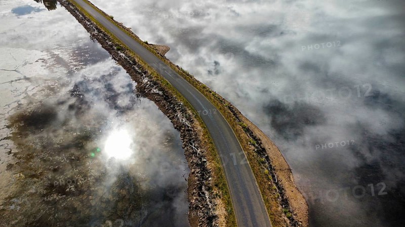 A long bridge over a shallow and calm lake on a cloudy day, photographed with a drone