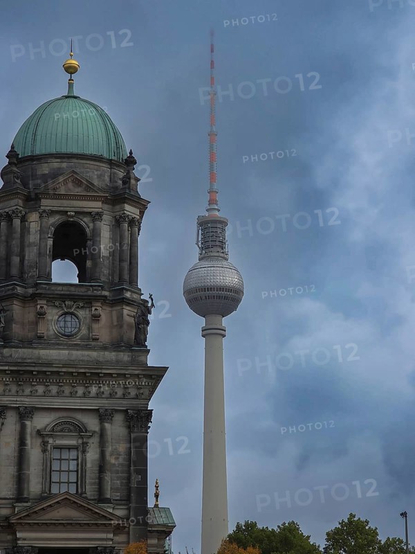 City view of Berlin Cathedral and TV Tower under grey, cloudy sky, contrasting mix of historic and modern architecture with subdued, dramatic atmosphere, corner of Berlin Cathedral in the background the TV Tower, Museum Island, Pleasure Garden, 10178 Berlin, Germany
