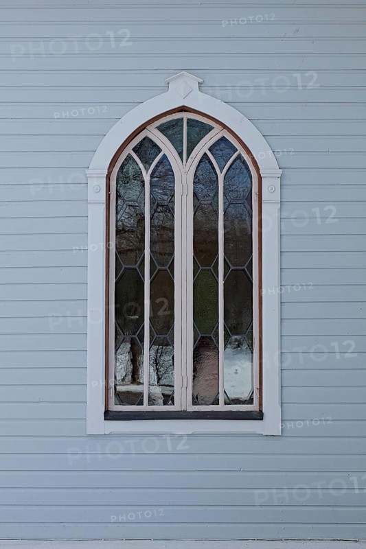 Closed old arched window with white frame on a light blue board wall, Mustio, Finland