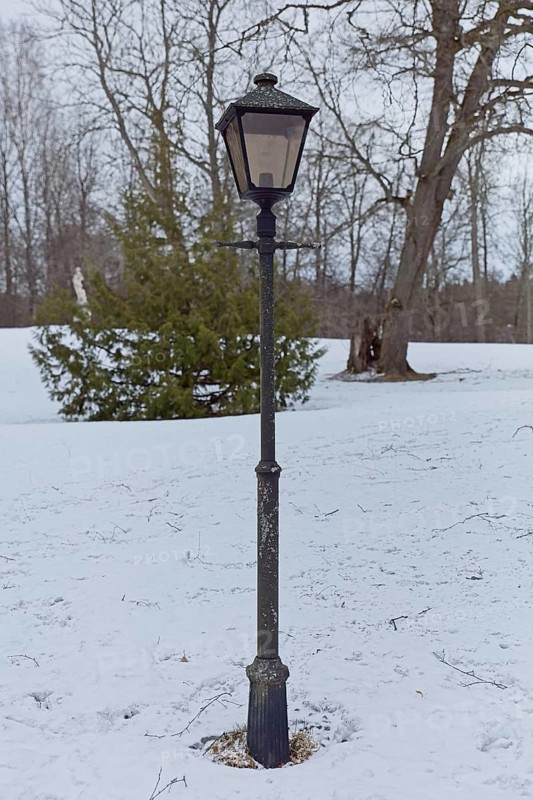 Lamp posti in park in cloudy winter weather with snow on the ground, Mustio, Finland