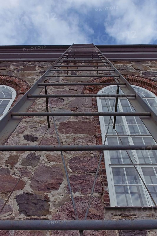Metal ladder going up to the roof of a stone building, Karjalohja, Finland