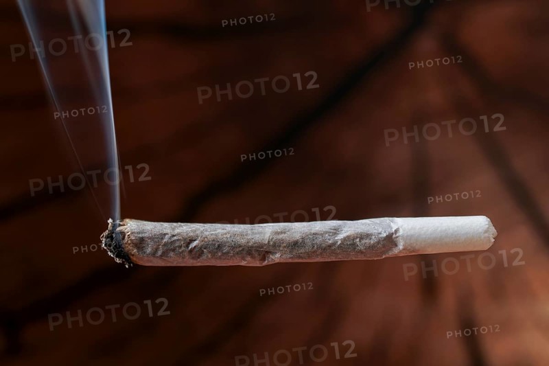 Burning joint producing smoke, highlighting drug use, cannabis culture, addiction, and illegal substances