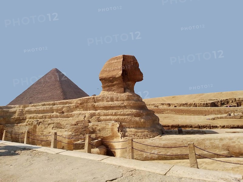 A close-up of the Great Sphinx, the symbol of the mythological deity of Ancient Egypt. The majestic Pyramid of Heops with its necropolis of the ancient pharaohs can be seen in the background. These landmarks, discovered during archaeological excavations on the Giza Plateau in the Sahara Desert, are among the Wonders of the World. Every year, tourists and travelers from around the world come here to experience the history of the ancient civilization of North Africa. Cairo, Egypt