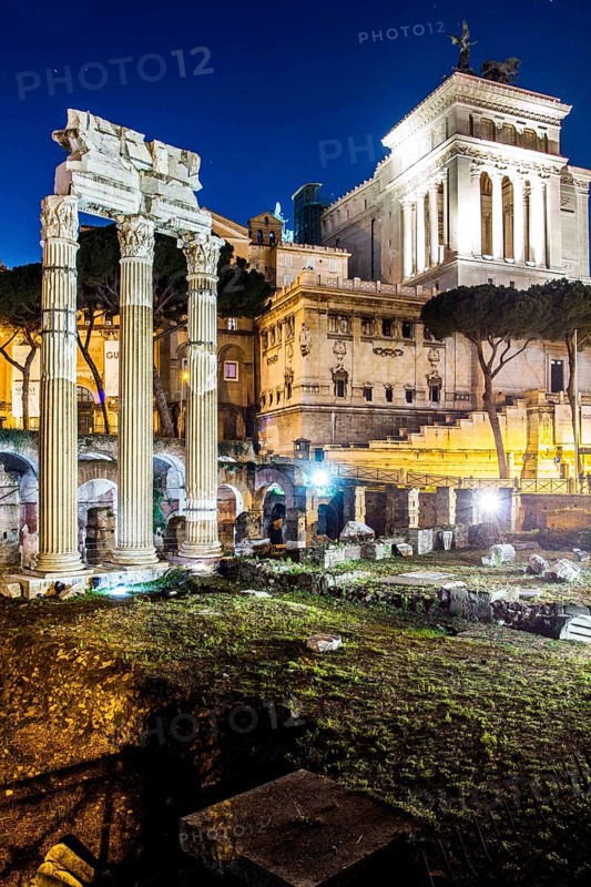 Forum of Caesar (Foro di Cesare), built between 1st century BC and 2nd century AD, with the colums of the Temple of Venus Genetrix in front and the Monument to Vittorio Emanuele II in the background, at night. Rome, Province of Rome, Italy