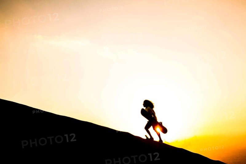 Silhouette of a sandboarder walking on the dunes of Caramucho, in Atacama Desert. Iquique, Tarapaca Region, Chile. 21.11.15