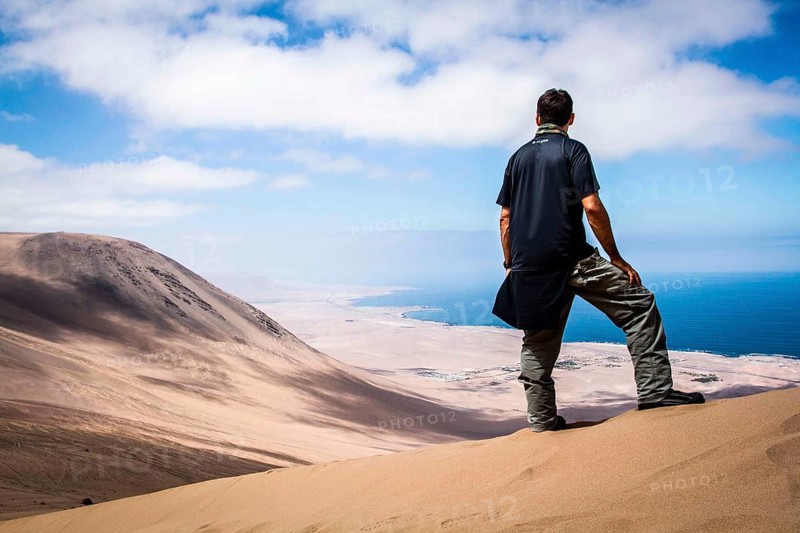 Young man looking at the view from Alto los Verdes, in Atacama Desert. Iquique, Tarapaca Region, Chile, 19.11.15