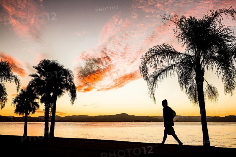 People walking on the sidewalk of Beira Mar Norte Avenue at sunset. Florianopolis, Santa Catarina, Brazil