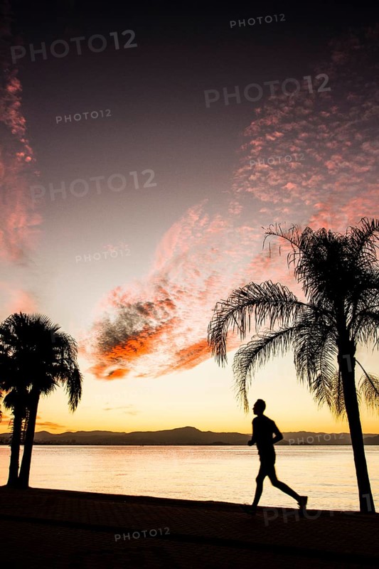 People walking on the sidewalk of Beira Mar Norte Avenue at sunset. Florianopolis, Santa Catarina, Brazil