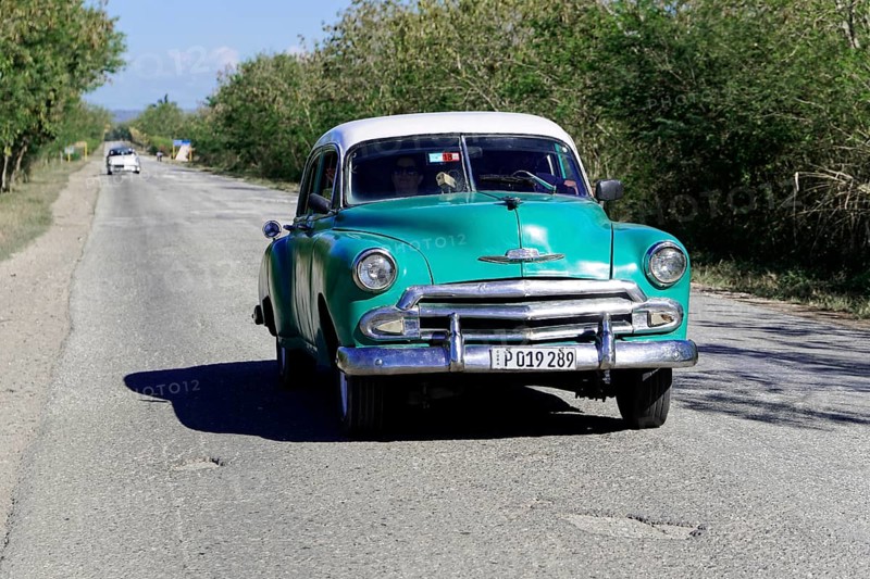 American classic car from the 1950s, near Holguin, Cuba, Vintage green car driving along a rural road along trees, Greater Antilles, Caribbean, Central America, America, Central America