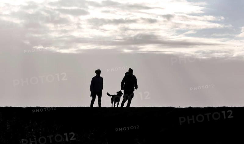 Couple with dog walking across a dike on the Baltic Sea, Fehmarn, 16.10.2025, Fehmarn, Schleswig-Holstein, Germany