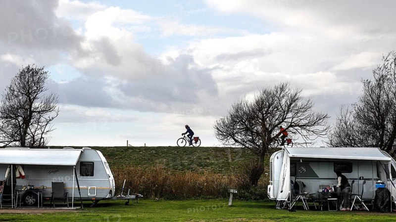 Caravan and motorhome on a campsite, a cyclist drives across the dike on the Baltic Sea, Fehmarn, 16.10.2025, Fehmarn, Schleswig-Holstein, Germany