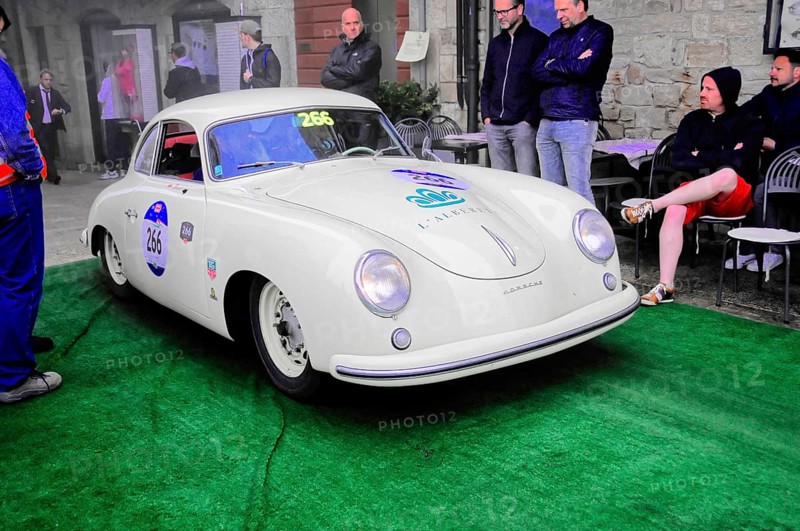White Porsche Coupé at a classic car rally on green carpet, spectators lean against the stone wall, Mille Miglia 2016, time control, checkpoint, SAN MARINO, classic car racing. San Marino, Italia