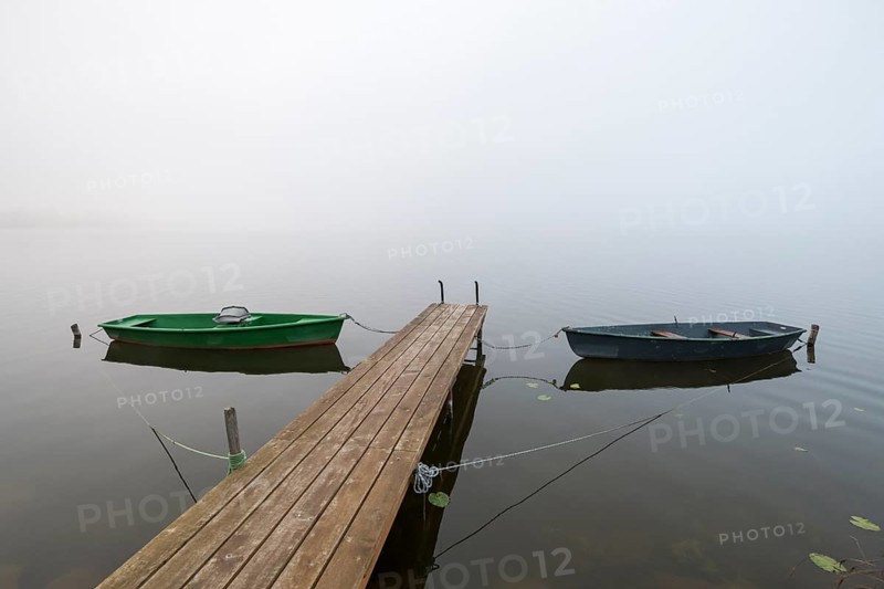 Two boats are moored on a wooden pier in fog, the atmosphere is calm and peaceful, Hopfensee, Ostallgäu, Bavaria, Germany
