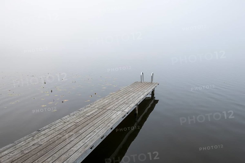 Empty wooden walkway in the misty water of a calm lake, Hopfensee, Ostallgäu, Bavaria, Germany