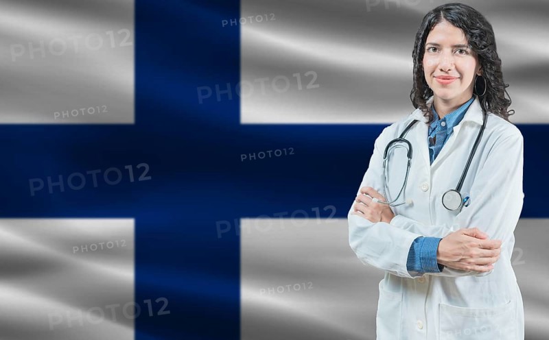 Finnish medicine and healthcare concept. Close up of doctor against Finland flag background