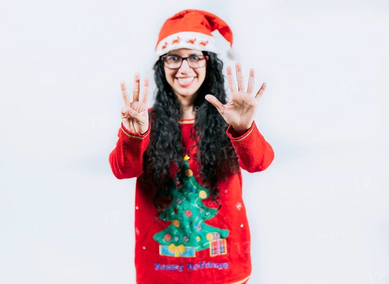 Happy girl in Christmas hat counting number EIGHT, isolated. Smiling girl in Christmas sweater counting number 8