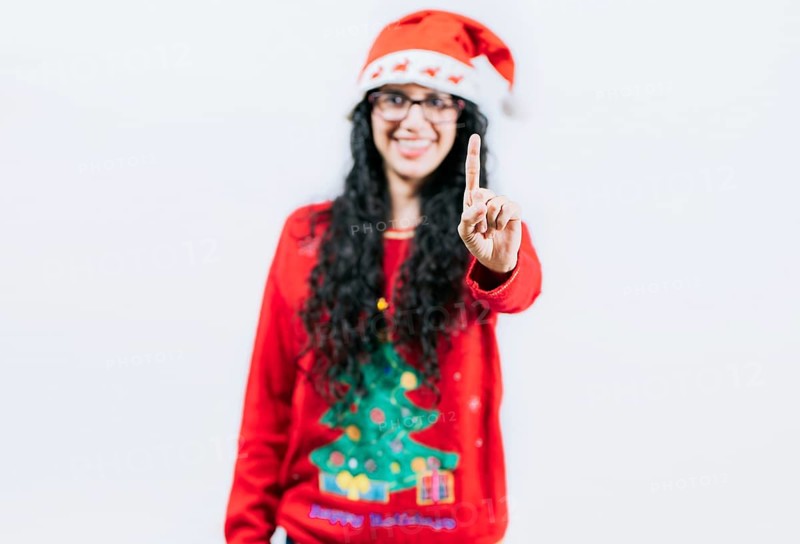 Happy girl in Christmas hat counting number ONE, isolated. Smiling girl in Christmas sweater counting number 1