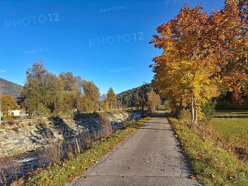 Autumn trail along a river, lined with colorful trees, Drau cycle path, Drava, South Tyrol, Italy