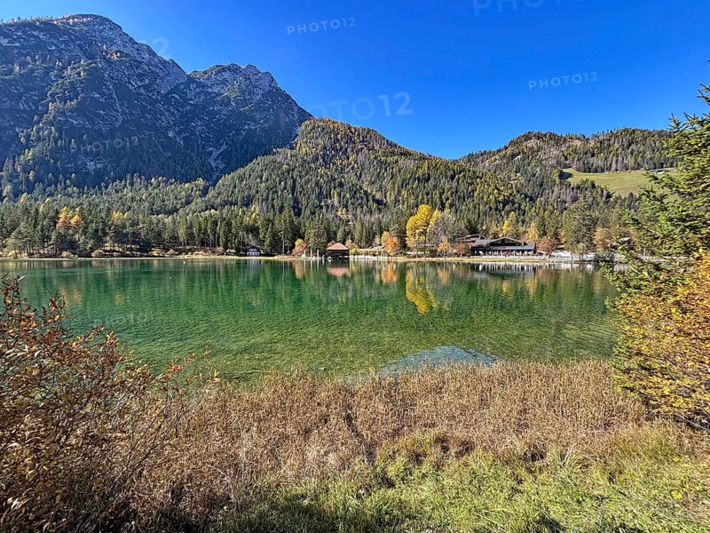 Calm lake with mountains in the background and colorful autumn leaves, Lake Toblach, Lake Dobbiaco, South Tyrol, Italy