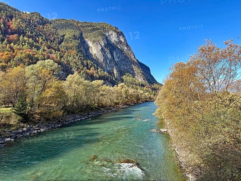 A clear river that snakes through an autumnal mountain landscape, under a clear sky, Drau, Drau cycle path, near Lienz, Tyrol, Austria