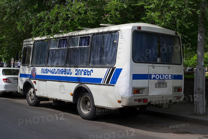 White police bus with Armenian lettering parked on the side of the road under shady trees, Yerevan, Yerevan, Armenia