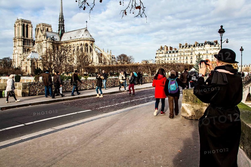 Tourists on Pont de l'Archevêché and Notre Dame Cathedral (Cathedrale Notre Dame de Paris) in the background. Paris, France. 02.01.13