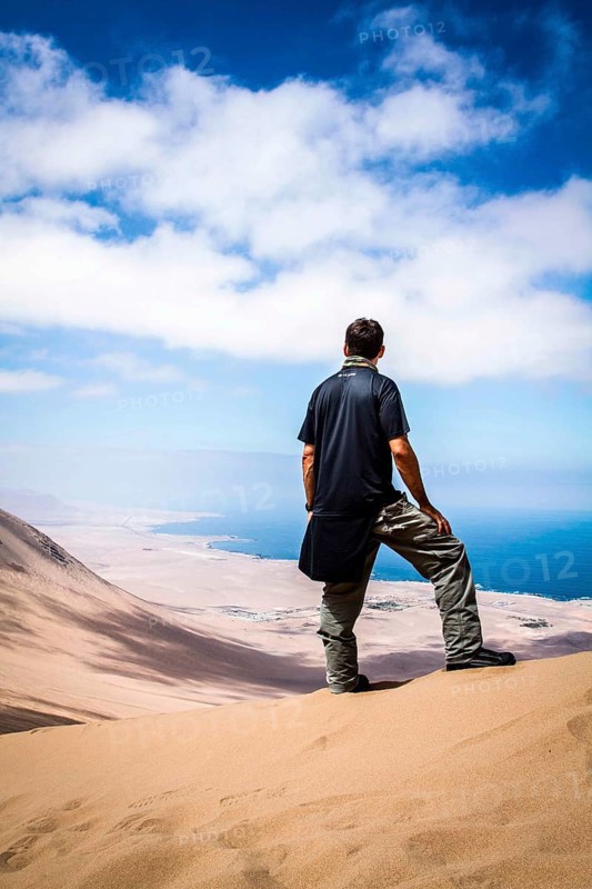 Young man looking at the view from Alto los Verdes, in Atacama Desert. Iquique, Tarapaca Region, Chile. 19.11.15