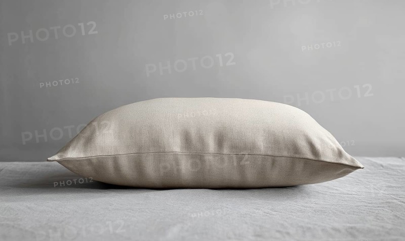 A side view of a beige pillow on a gray surface, emphasizing smooth fabric. AI generated