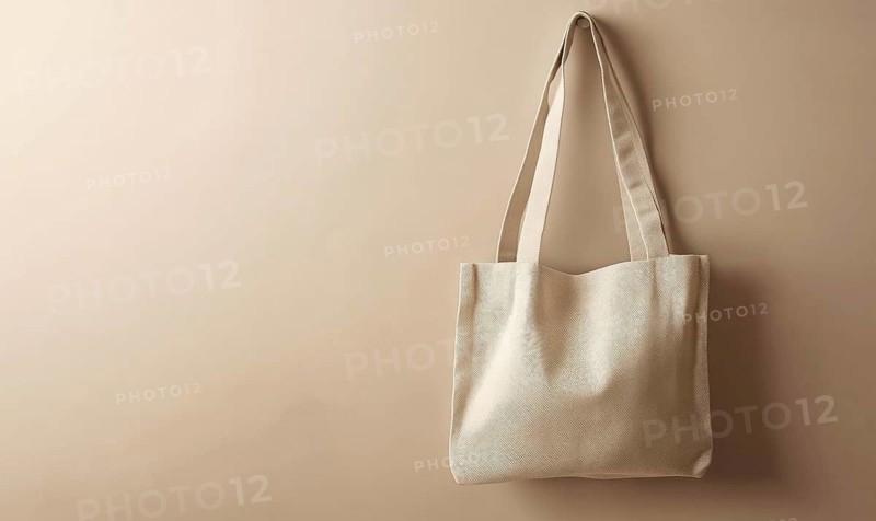 A tan tote bag is hanging on a wall. The bag is made of a light material and has a simple design. Concept of minimalism and simplicity. AI generated