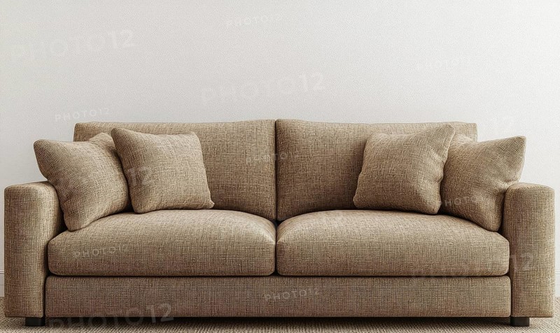 A brown couch with pillows on it. The couch is in a room with a white wall. AI generated