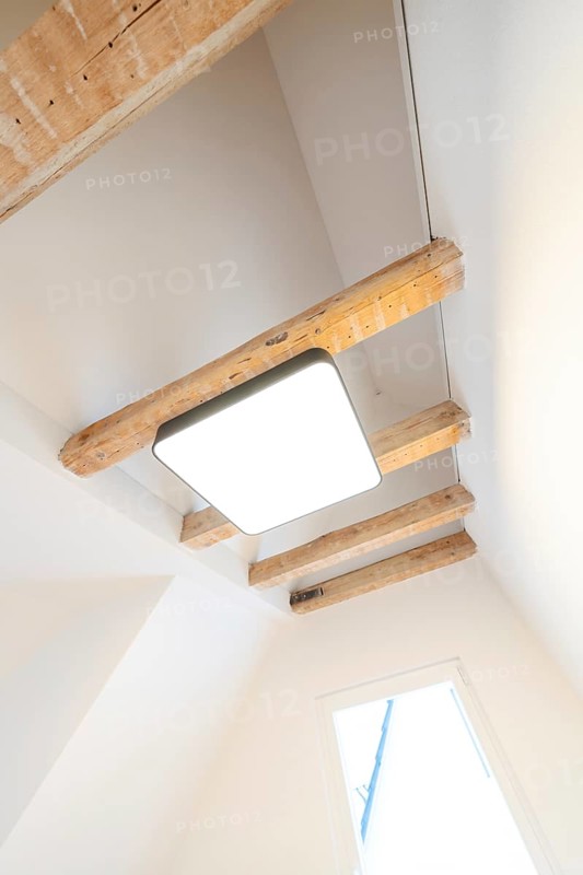 Bright room with visible wooden beams and modern ceiling light under a sloping roof, house renovation, energy renovation, Metzingen, Germany