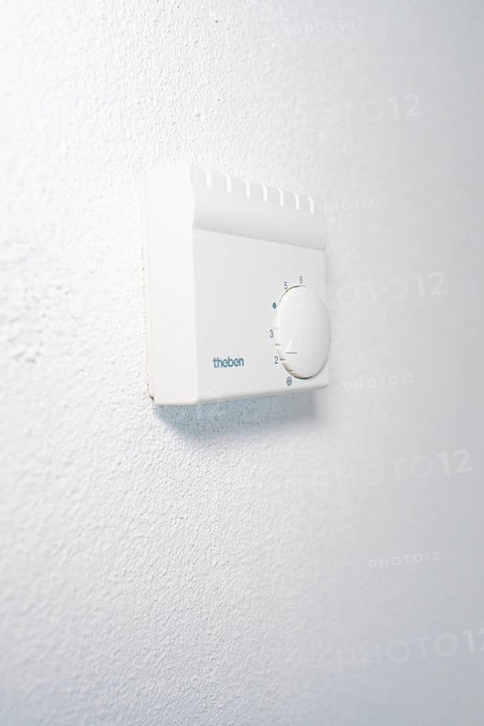 Wall thermostat with rotary knob on textured white wall in a quiet, bright atmosphere, house renovation, energy renovation, Metzingen, Germany