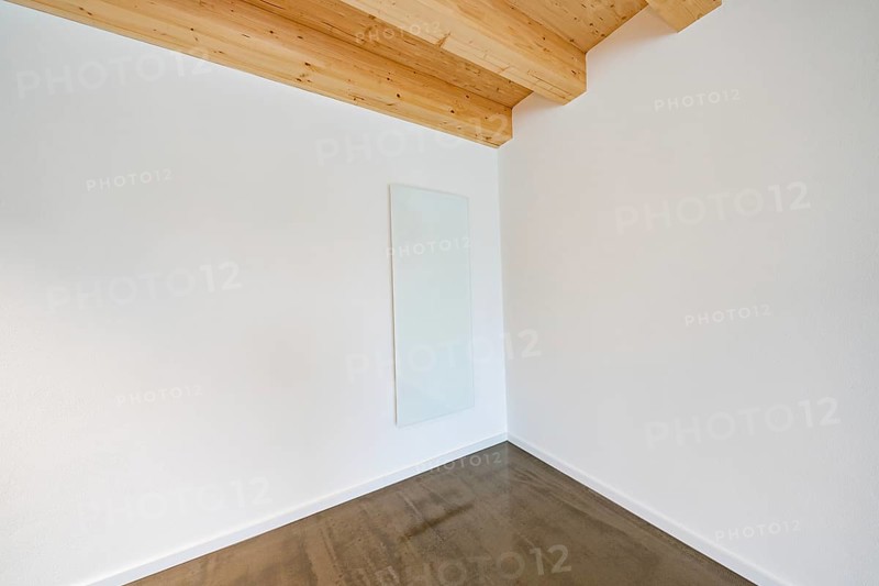 Bright corner with glass heating panel on white wall under wooden beam ceiling, reduced appearance, house renovation, energy renovation, Metzingen, Germany