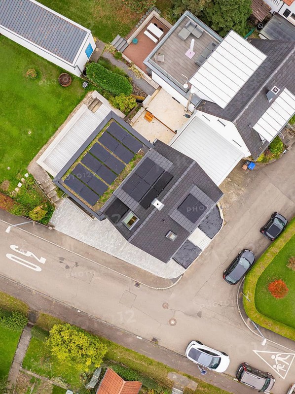 Bird's-eye view of corner house with PV systems on roof and carport, paved driveway and traffic-calmed road with 30 markings, house renovation, energy renovation, Metzingen, Germany