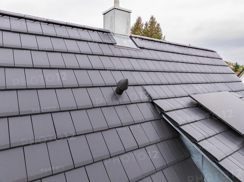 Detail of an anthracite-colored tile roof with roof vent and sheet metal connections under cloudy sky, house renovation, energy renovation, Metzingen, Germany