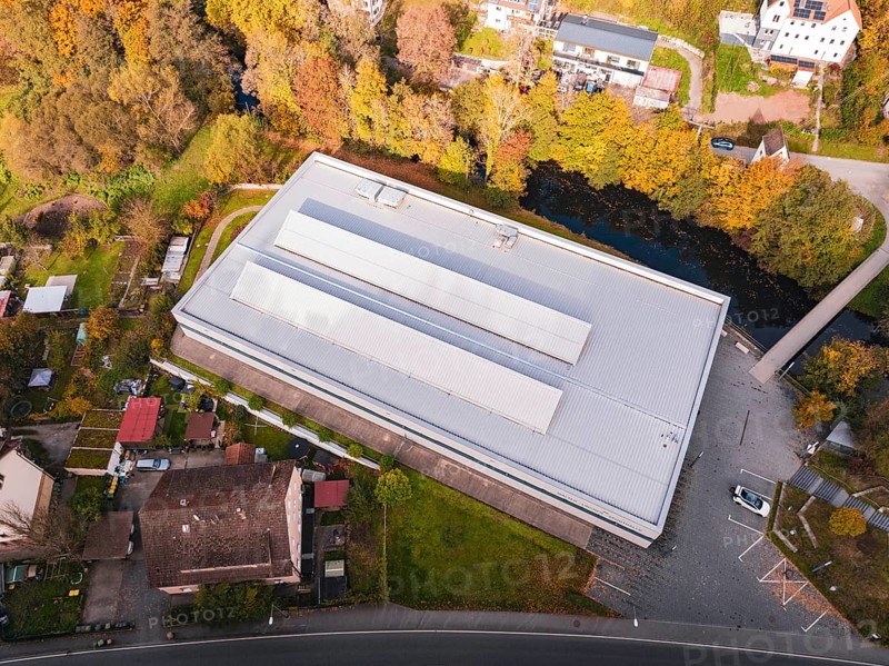 Flat sports hall in the midst of autumn surroundings with adjacent village and river, Walter Lindner Sporthalle Calw, Black Forest, Germany