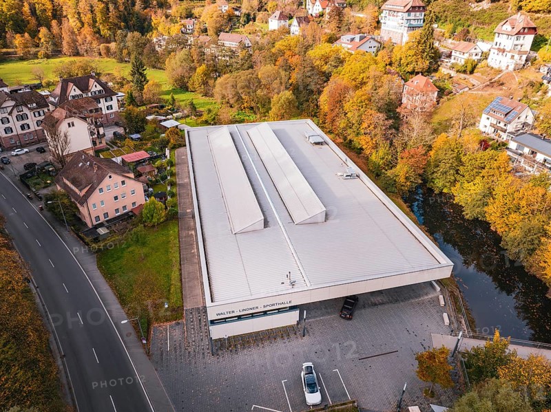 Sports hall in autumn surroundings with colorful trees and adjacent street, Walter Lindner Sporthalle Calw, Black Forest, Germany